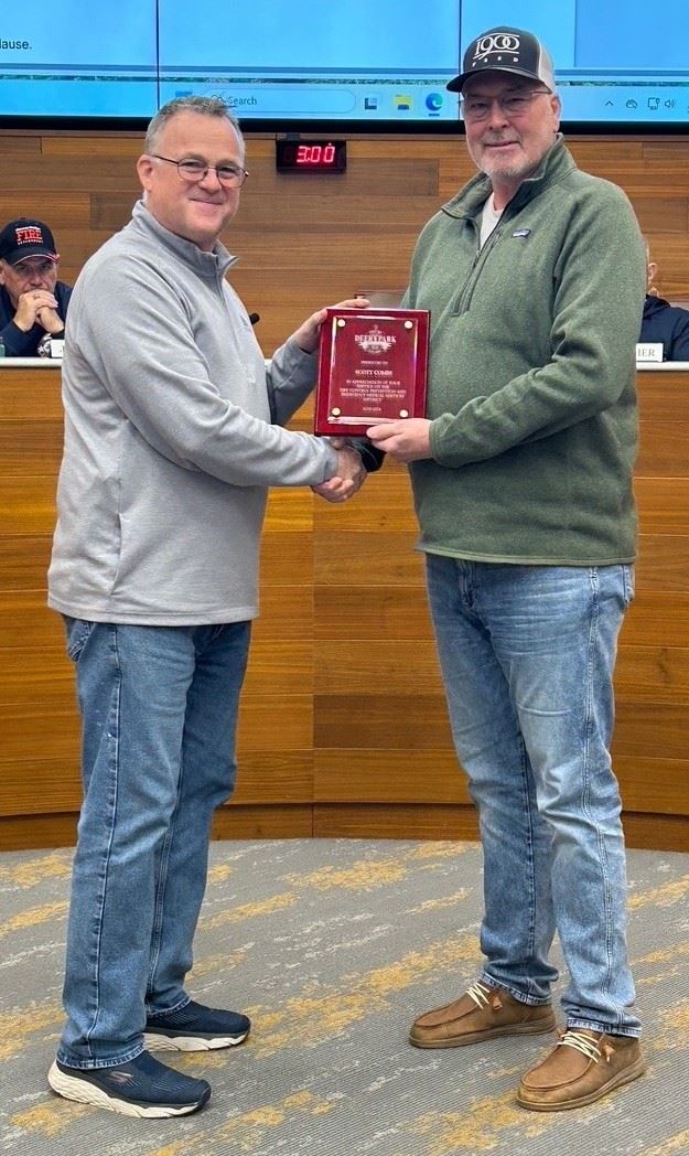 Two men standing in the middle of the room holding a plaque of appreciation.