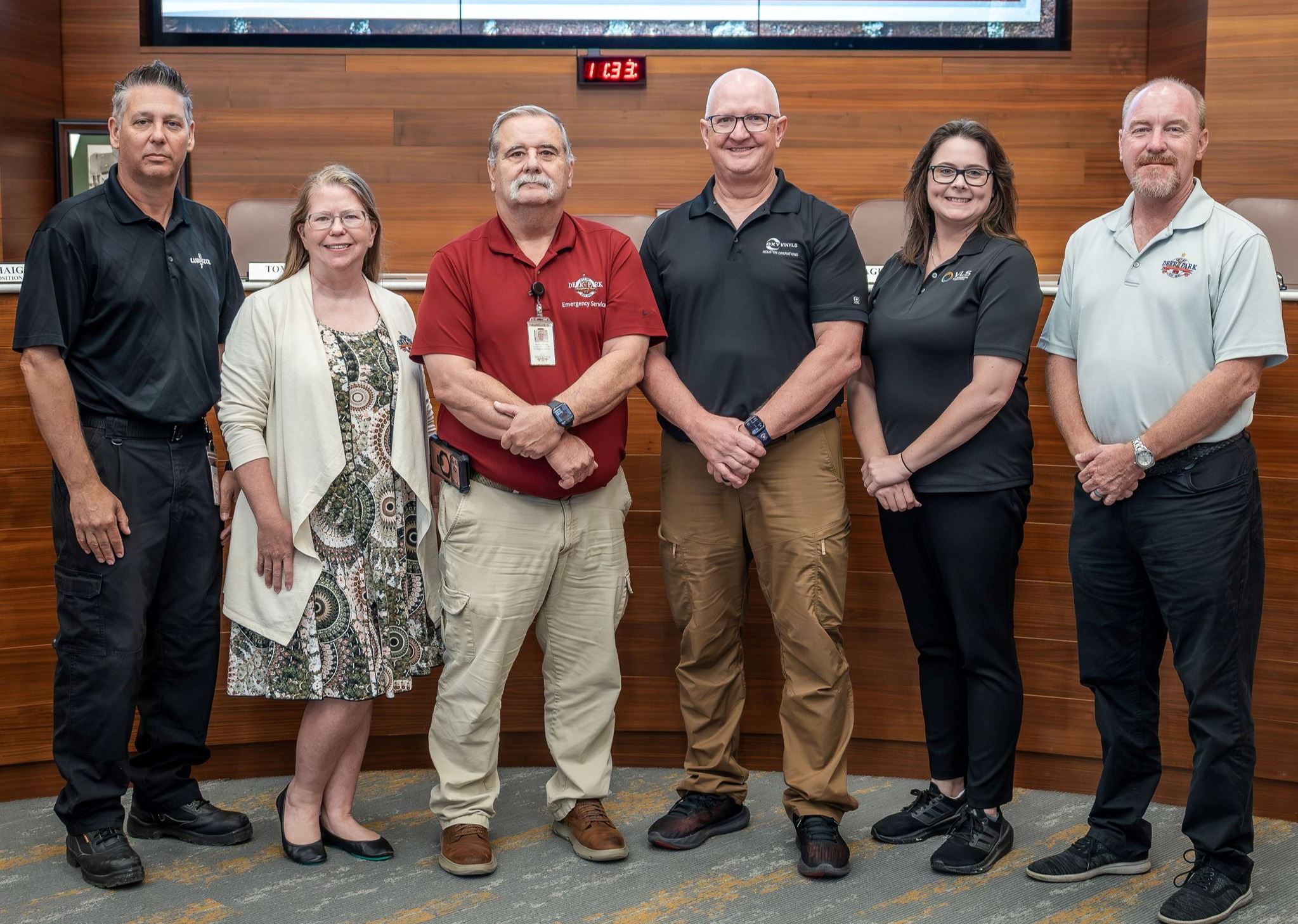 Six men and women are standing in front of a dais in a row. 
